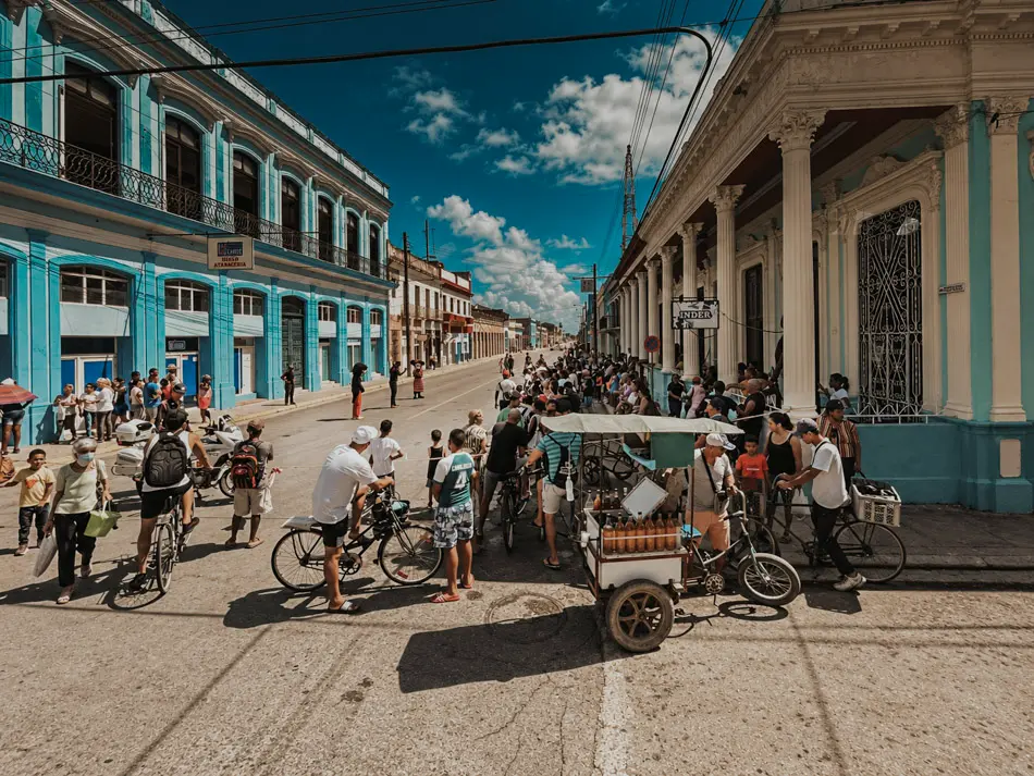 Busy Havana street with cyclists, pedestrians, market activity and colourful Cuban architecture